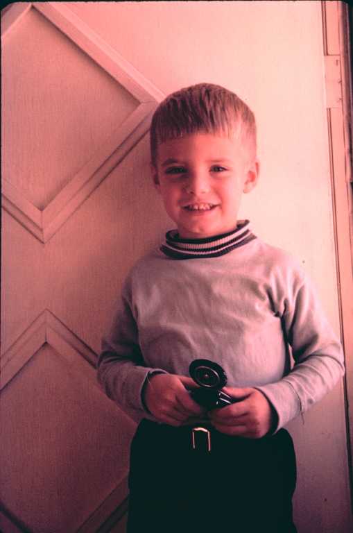 Billy holding exposure meter at front door, December 1957